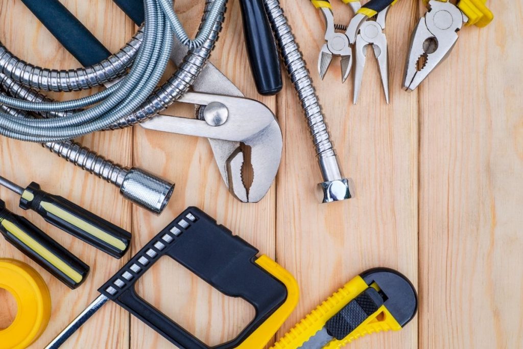 An assortment of hand tools, including drills and measuring tapes, organized on a wooden table, highlighting a DIY environment.